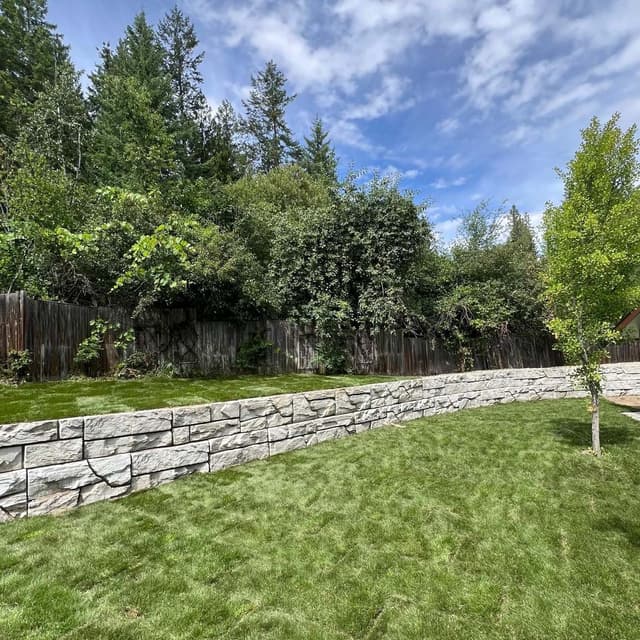 After photo of a backyard transformation with a new retaining wall and leveled lawn